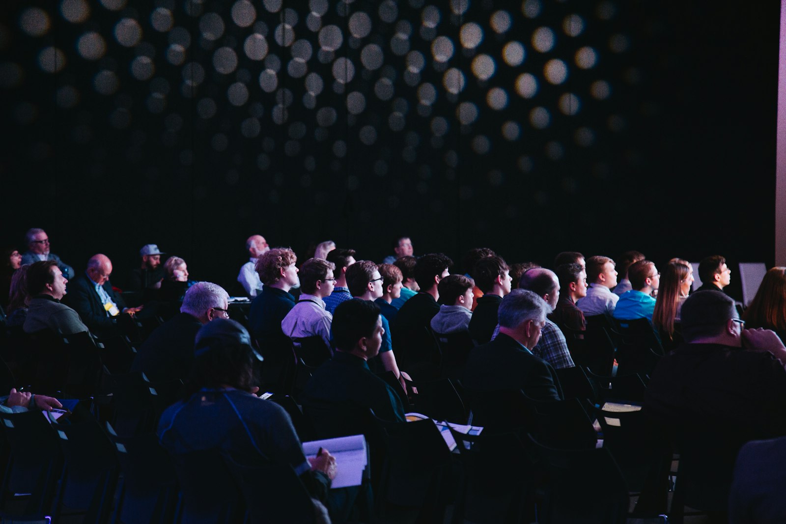 Conference audience packed under stage lights