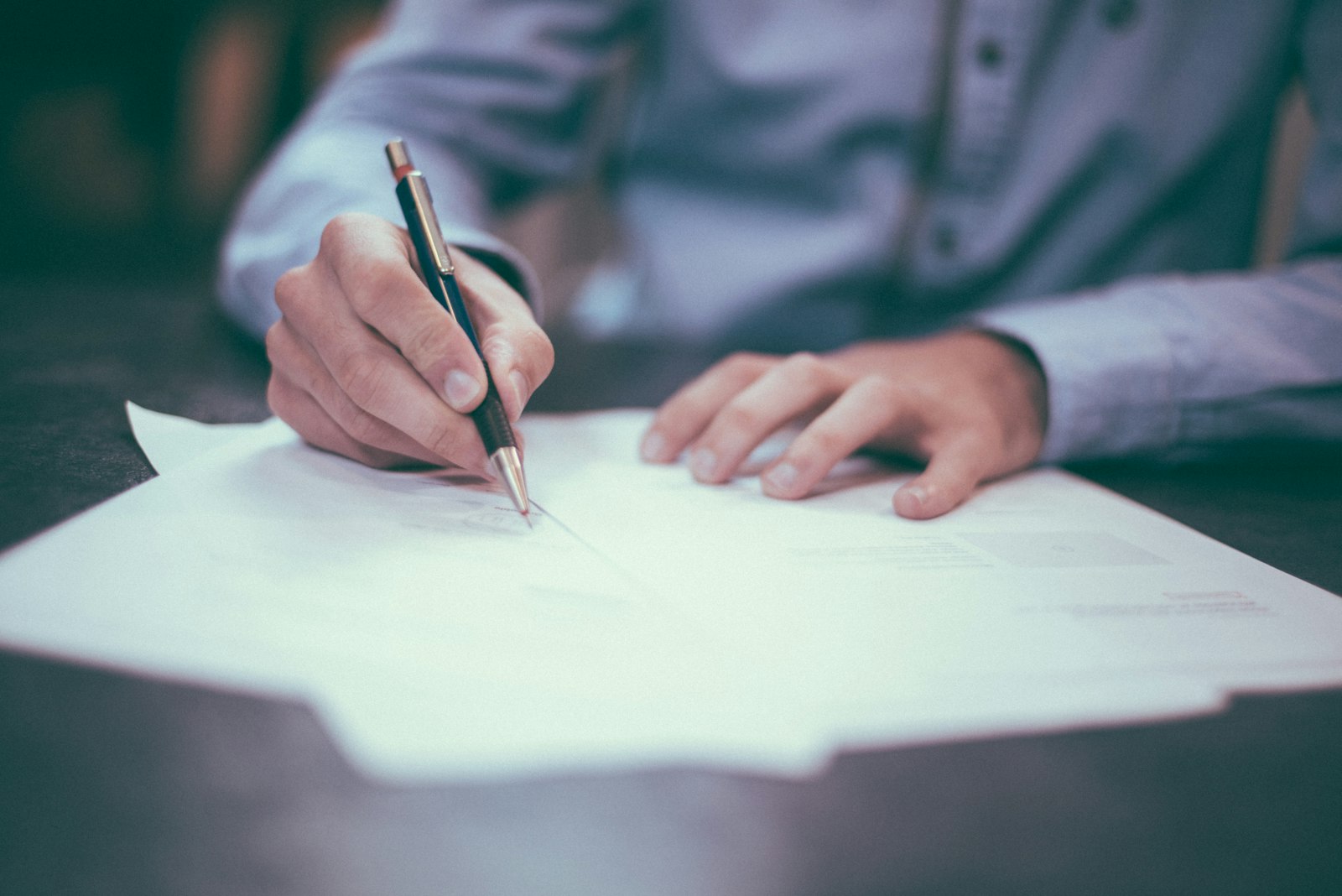 A professional signing a certification document at a desk